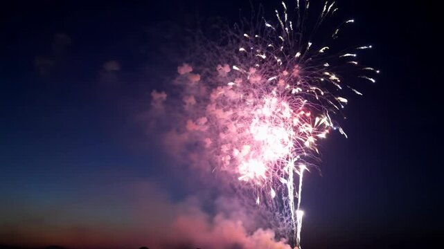 Awe-inspiring grand fireworks erupting vibrantly red, blue, purple, pink, yellow across a velvety dark evening sky, with clear left copy space. Concept of triumph and optimism