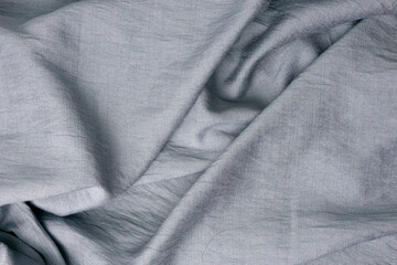 Fototapeta premium Soft gray fabric texture background with natural folds and wrinkles. Minimal textile surface in neutral tone, suitable for fashion, interior, luxury branding, backdrop, and abstract background design.