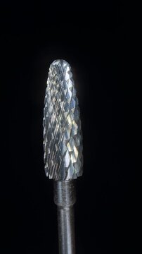 Vertical video. Professional Manicure Drill Bit With Sharp Metal Texture, Macro Slow Motion Rotation of Carbide Nail Tool on Black Background, Precision Beauty Equipment and Nail Care Industry