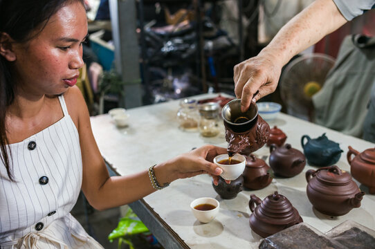 Asian woman drinking hot tea at a local market stall in Kaohsiung, Taiwan