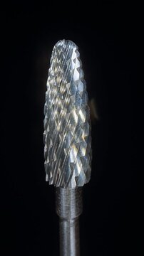 Vertical video. Rotating Professional Manicure Drill Bit in Macro Dolly Slider Closeup, Reflective Metal Milling Surface With Sharp Spiral Texture on Black Background
