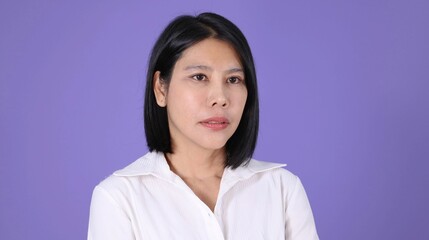 Fototapeta premium Serious Asian Businesswoman in White Shirt Against Purple Background