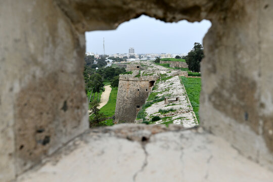 A framed perspective looking out through a narrow stone window or embrasure of Famagusta Castle.