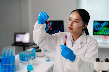 Young Asian woman genetic researcher wearing protective eyewear and gloves, analyzing human blood...