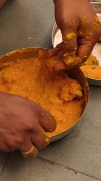 Close-up of hands extracting fresh mango pulp for traditional Aamras preparation, showcasing homemade Indian cuisine, tropical fruit texture, and authentic culinary process.