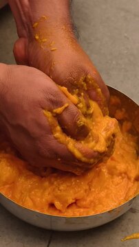 Close-up of hands extracting fresh mango pulp for traditional Aamras preparation, showcasing homemade Indian cuisine, tropical fruit texture, and authentic culinary process.