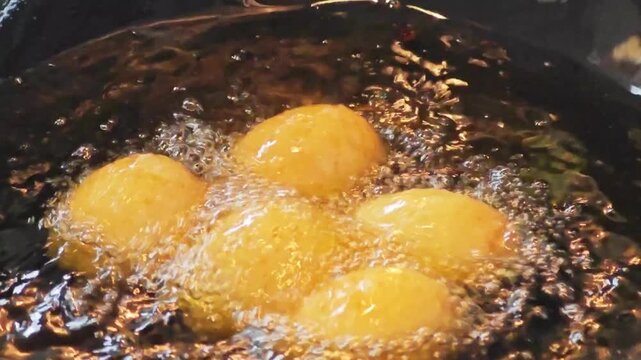 Hard-boiled eggs deep frying in a hot wok with boiling oil.
