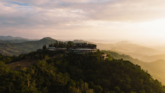 Aerial view of the Temple of Leah in Busay nestled among lush green hills and tropical forests during a golden sunset in Cebu City, Central Visayas, Philippines.