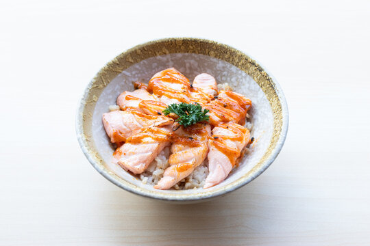 Delicious Japanese Salmon Aburi Don featuring seared salmon sashimi topped with spicy mentaiko mayonnaise sauce over rice in a ceramic bowl.