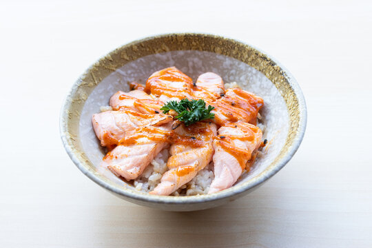 Delicious Japanese Salmon Aburi Don featuring seared salmon sashimi topped with spicy mentaiko mayonnaise sauce over rice in a ceramic bowl.