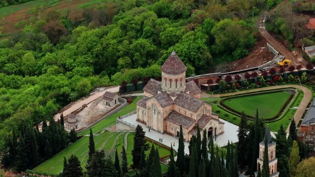 Aerial drone view of Bodbe Monastery in Georgia set on a green hilltop overlooking valleys, forests, and scenic countryside.