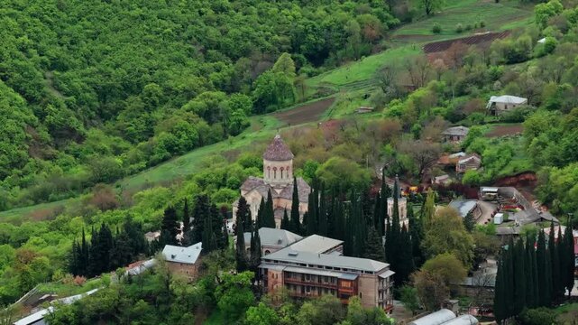 Aerial drone view of Bodbe Monastery in Georgia on a hilltop surrounded by lush countryside, mountains and peaceful scenic landscapes.