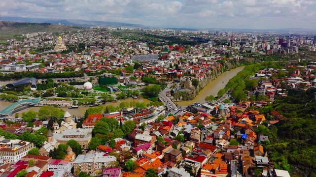 Cinematic drone footage of Tbilisi cityscape featuring urban architecture, winding river views, and surrounding Caucasus hills.
