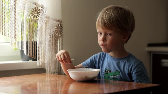 Young boy eating cereal for breakfast at home