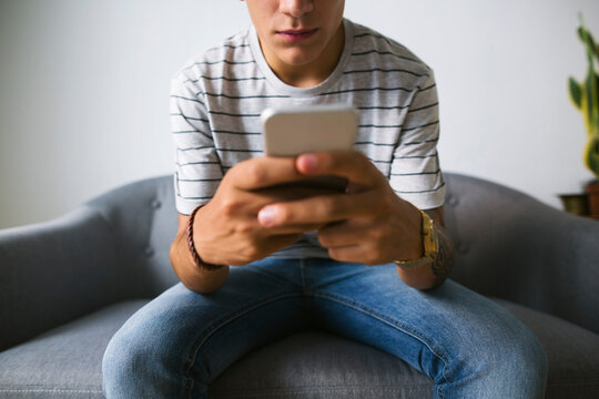 Teenage boy sitting on couch at home using cell phone