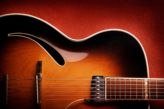 Guitar leaning against red wall