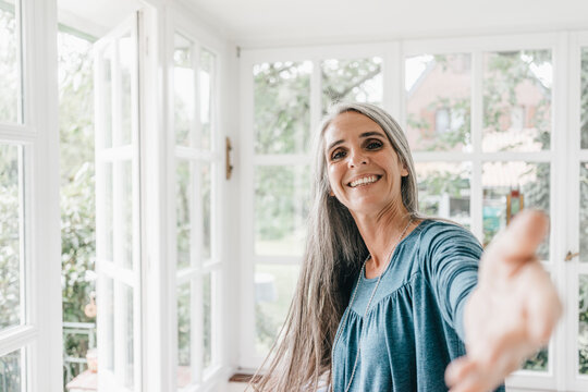 Portrait of smiling woman inviting viewer in her winter garden