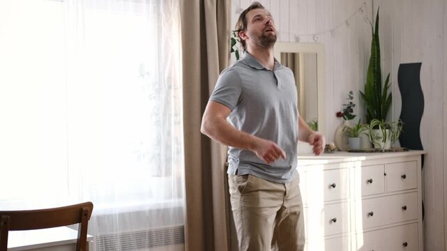 Handsome bearded man dance, have fun at home listens song, moves to music, feels overjoyed, celebrate good news, relish carefree life looks happy. Young adult male twirls, grooves, dancing in kitchen