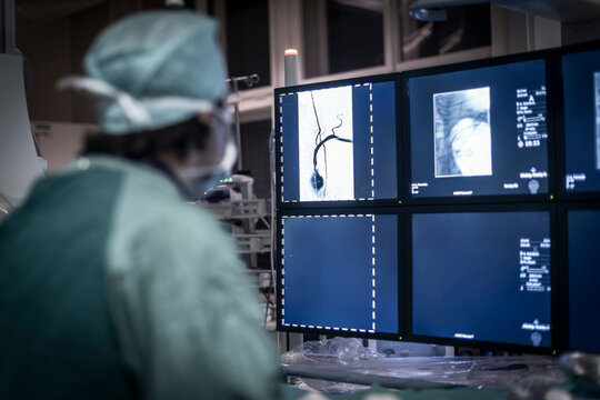 Neuroradiologist in scrubs looking at monitor