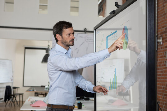 Businessman handling graphs on screen in office