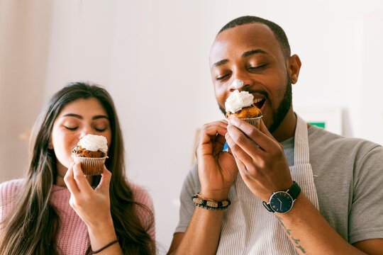 Young couple having fun, eating fresh cupcakes