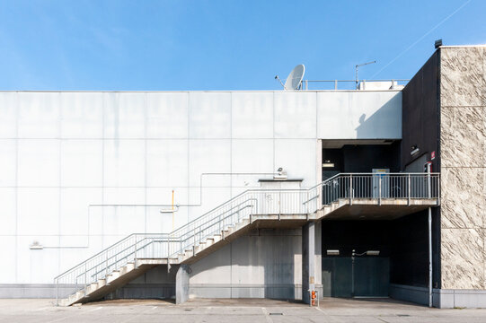 Edificio moderno minimalista caratterizzato da una facciata piana e dai colori chiari. Una scala metallica con ringhiera &egrave; fissata all'esterno e conduce al piano superiore. Architettura contemporanea.