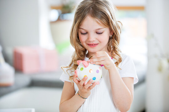 Girl throwing coin into piggy bank
