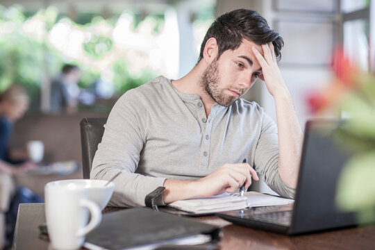 Frustrated man sitting at dining room table working at home