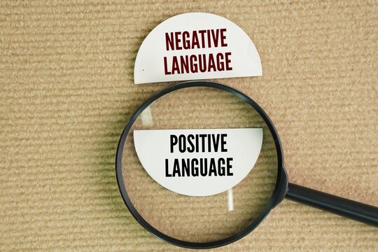 Magnifying glass and paper with the words Positive vs Negative Language. Negative language reflects a negative attitude and mood, whereas positive language communicates a supportive, confident