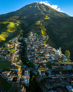 Aerial view of the colorful Butuh village on the slopes of Mount Sumbing with terraced fields and a mosque, Central Java, Indonesia.