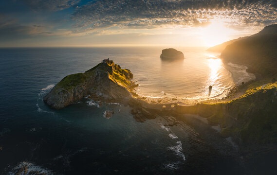 Aerial view of Gaztelugatxe islet with its winding stone bridge and hermitage under a golden sunset sky Gaztelugatxeko Doniene, Basque Country, Spain.
