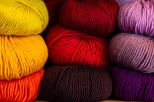 Colorful wool yarn balls stacked as vibrant textile background