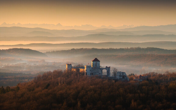 Aerial view of the Krakow-Czestochowa Upland with a medieval castle ruin amidst misty forests and distant mountain peaks at sunset Krakow County, Lesser Poland Voivode, Poland.