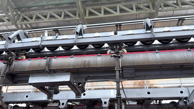 Cable Car Pulley System Inside Ropeway Station. Close-up view of a cable car pulley system with steel rope and metal machinery inside a ropeway station.