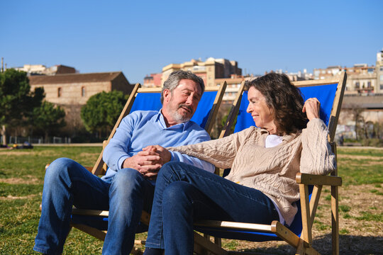 Senior couple relaxing on deck chairs in a barcelona park