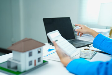 Fototapeta premium Financial planner calculating and analyzing data on a calculator and laptop, managing finances for real estate investment, and planning property market growth