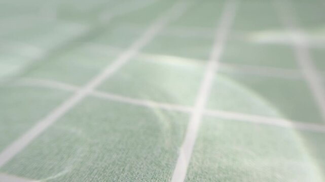 Water caustic sunlight reflections on green ceramic tiles with grout lines, abstract pool ripples, and light refraction creating a soothing and hypnotic background