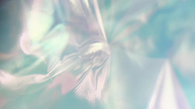 Holographic iridescent foil reflecting beautiful pastel colors. Abstract creative background with soft light leaks and liquid texture creating a surreal and dreamy mood