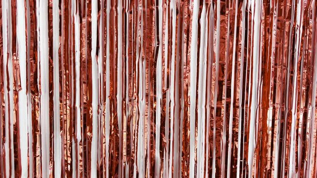 Shiny red gold tinsel foil fringe curtain gently swaying and reflecting light against a solid white background, creating a sparkling, festive, and elegant party decoration