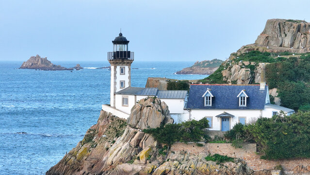 Aerial view of Louet island featuring the historic lighthouse and keeper's cottage perched on rocky cliffs overlooking the Morlaix Bay in Carantec, Brittany, France.