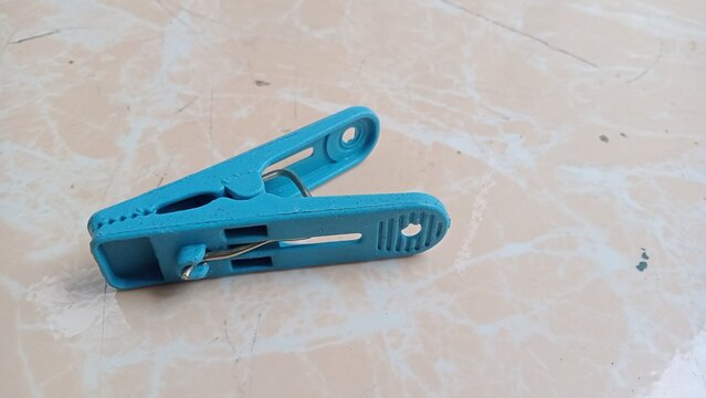 Single blue plastic clothespin on a marble textured background