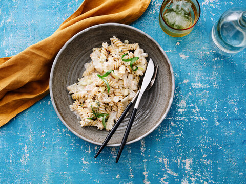The dish features rotini pasta coated in a creamy sauce and garnished with fresh herbs. This image is suitable for restaurant menus, food blogs, and promotional materials highlighting lunch options