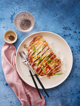 This dish features grilled chicken served over a bed of rice, garnished with fresh vegetables. It is suitable for meal prep services, healthy eating campaigns, and restaurant menus