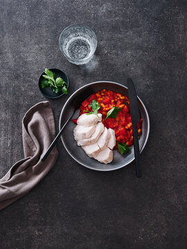 This image features sliced chicken breast served with a hearty vegetable sauce, garnished with fresh herbs. Ideal for restaurant menus, meal prep blogs, and advertising healthy eating campaigns