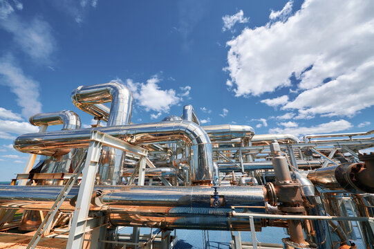 Pipelines and structures of a chemical plant under a clear blue sky, highlighting industrial processes at work during daytime