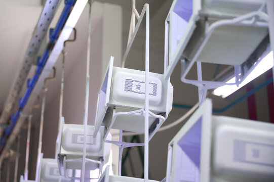 Microwave oven casings moving along overhead conveyor in powder coating workshop