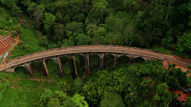 Aerial drone view of Ella&rsquo;s Nine Arches Bridge set in a dramatic green valley with misty mountains and dense jungle surroundings.
