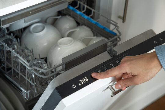 female hand setting cycle on dishwasher