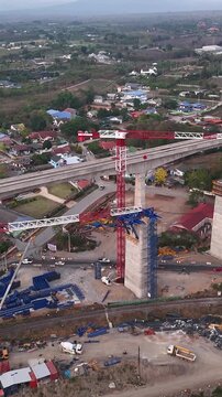 Vertical drone footage of elevated high-speed rail viaduct under construction with tower cranes in Pak Chong, Thailand.