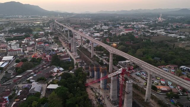 Aerial of Construction site, cranes assembling elevated bridge for Thailand&rsquo;s first high-speed railway, in Pak Chong during Sunset.